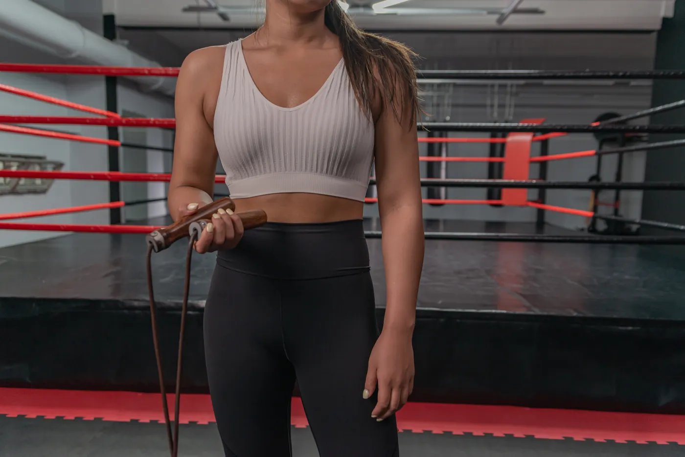 Coach holding a wooden-handled skipping rope beside a training ring