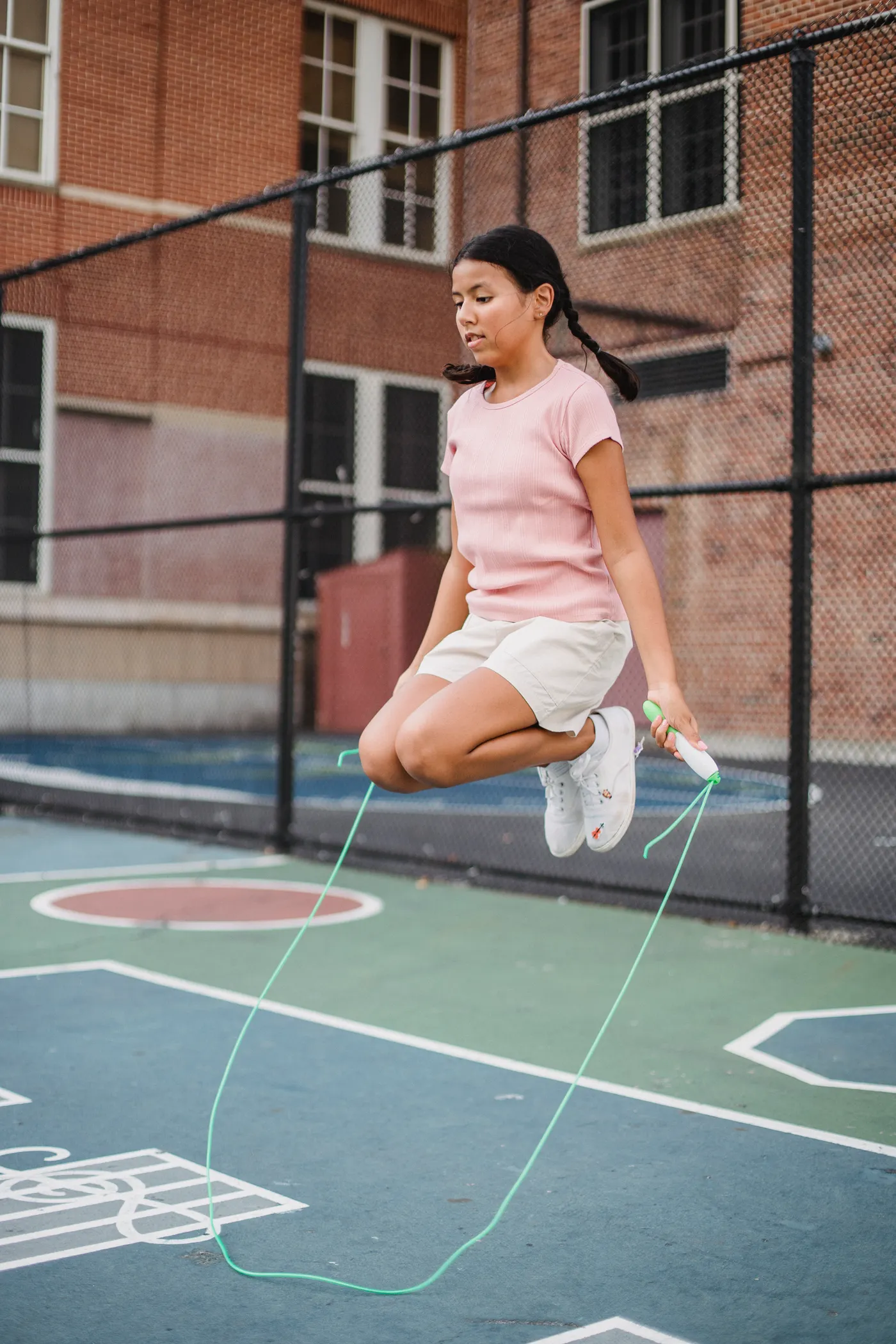 Teenager jumping rope on an outdoor basketball court